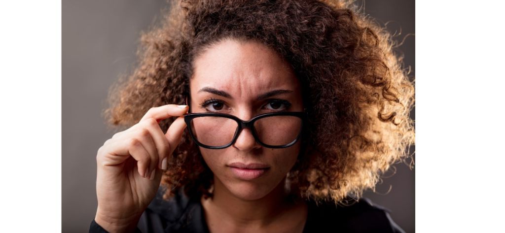 A skeptical woman lowering her glasses to take a closer look, illustrating how homeowners learn to spot dual tracking warning signs