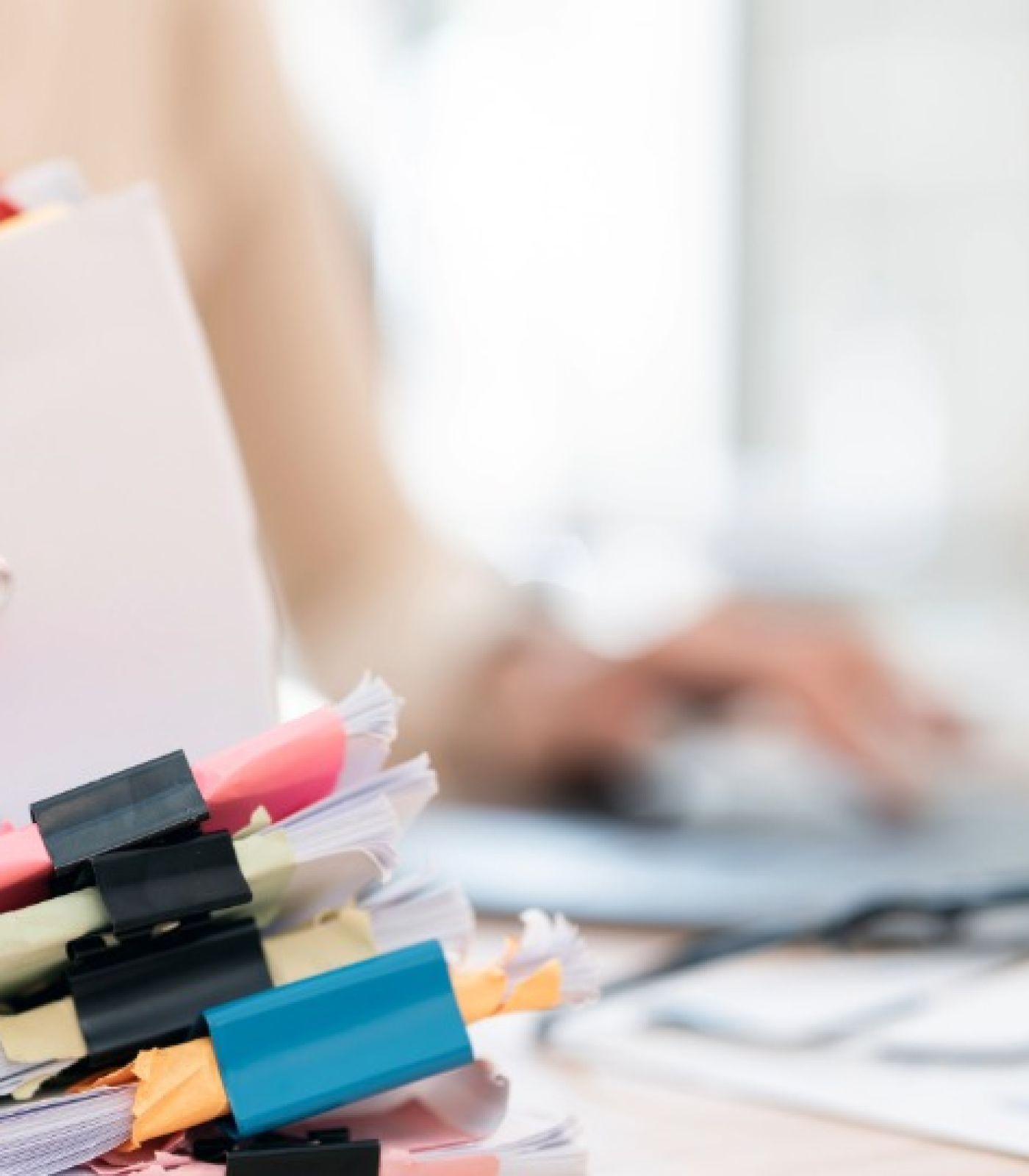 A person sorting through stacks of clipped paperwork and files at a laptop, illustrating the repeated document requests common in loan modification and dual tracking