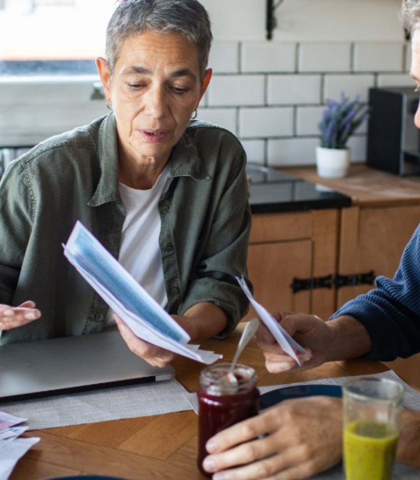 A couple sitting at their kitchen table going through household bills and paperwork together.