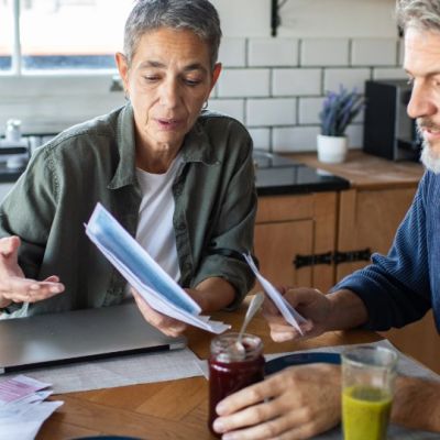 A couple sitting at their kitchen table going through household bills and paperwork together.